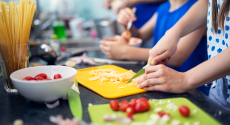 Students in a kitchen chopping vegetables and preparing a meal 